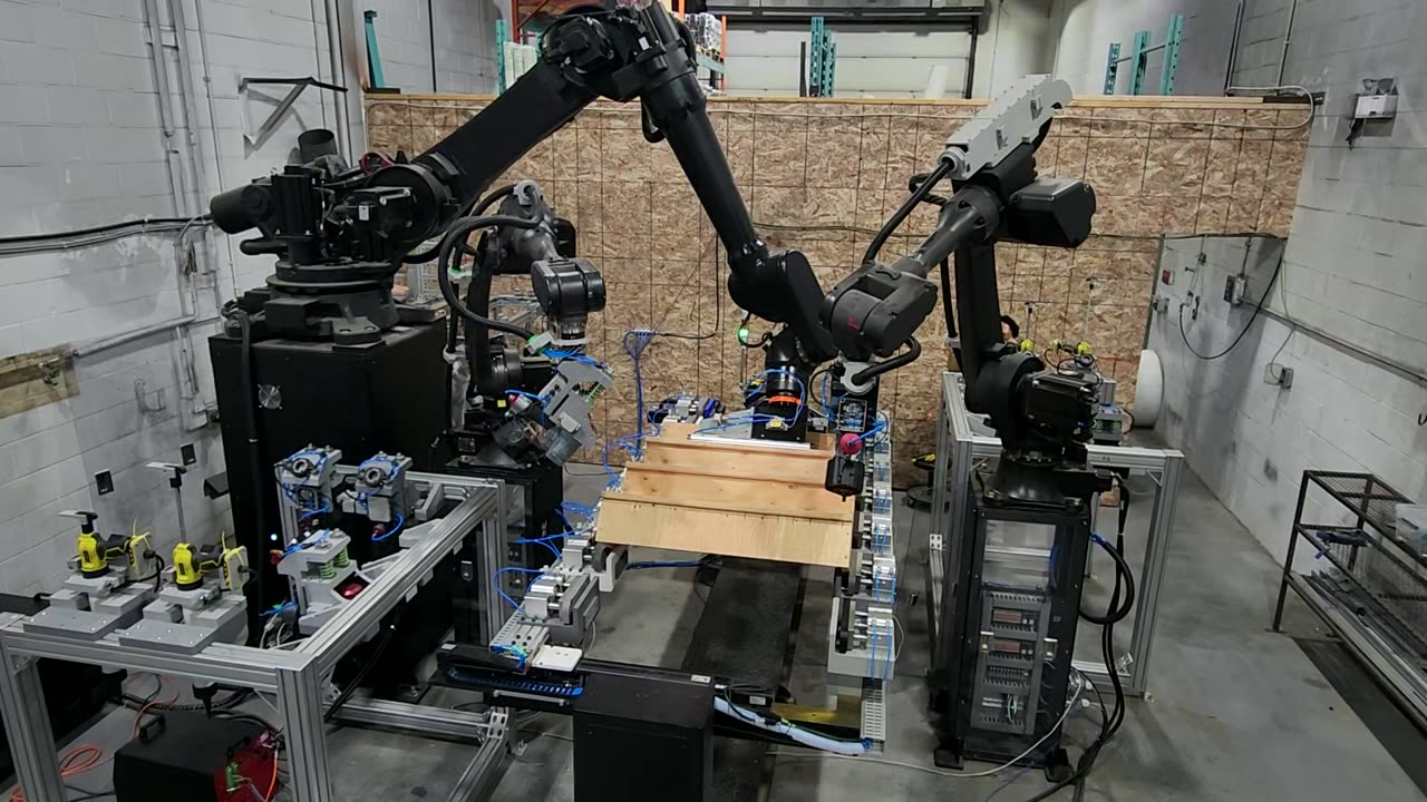 Three robots assembling a wooden staircase in the Stairbotics prototype cell